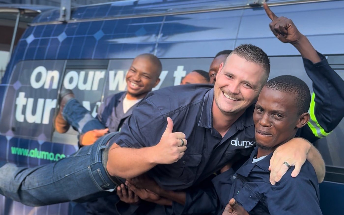 Members of the Alumo team outside a branded company van